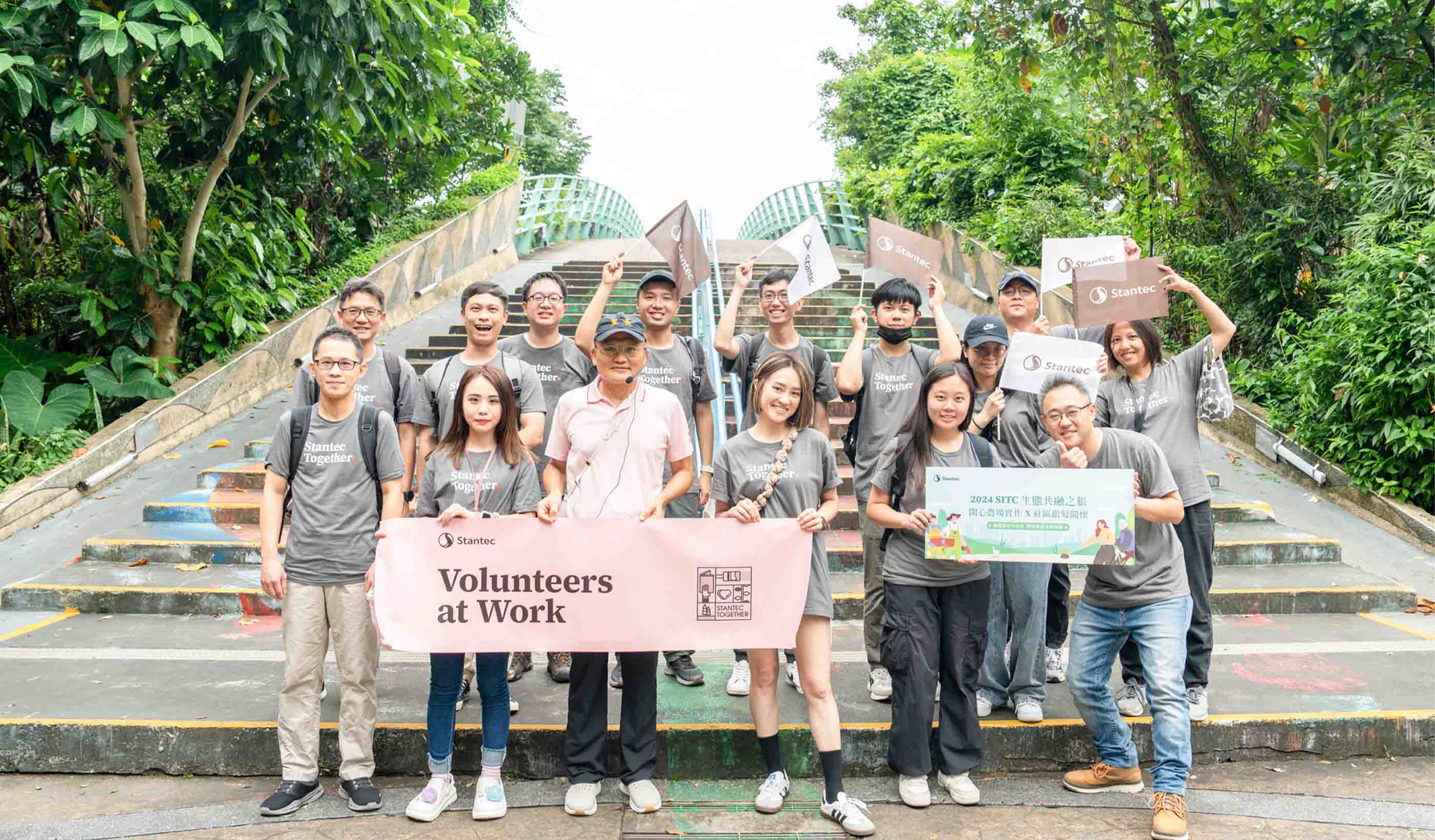 A group of people with signs standing on stairs with plants on both sides